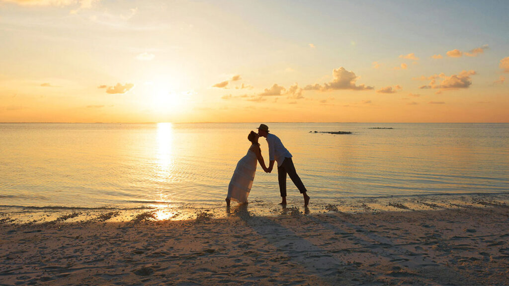 a couple kisses on the shore at sunset