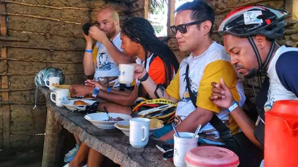 a group of 4 tourists eat at the humble table of an African village