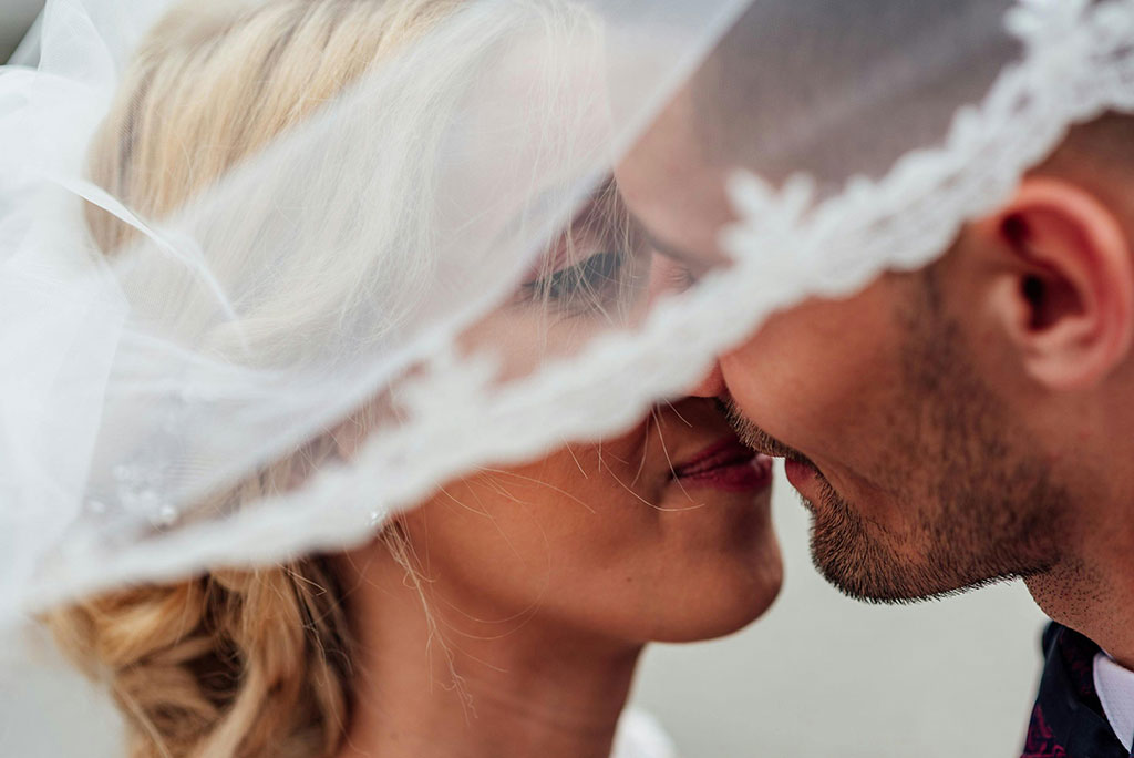 married couple kissing behind the wedding veil