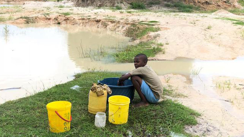 a child near a puddle of water with colored buckets