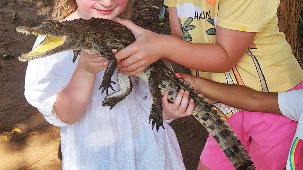 three little girls holding a baby crocodile in their hands